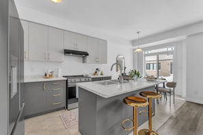 A modern kitchen with grey cabinets, a central island, and bar stools.