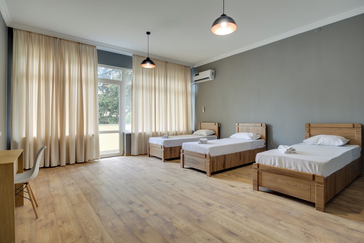 A room with three wooden beds, a desk, and a chair.