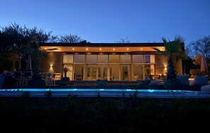 Una moderna casa con piscina, ampie finestre e area relax esterna.