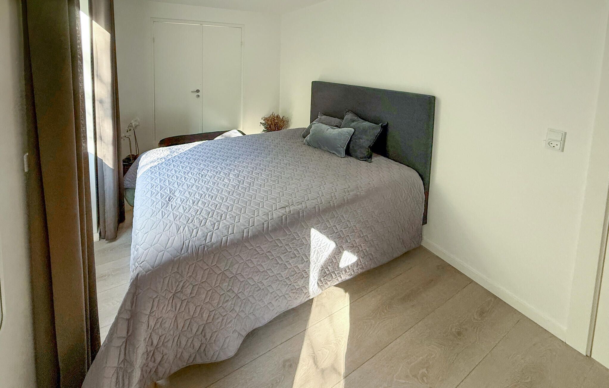 Un dormitorio con cama, mesita de noche y ventana.