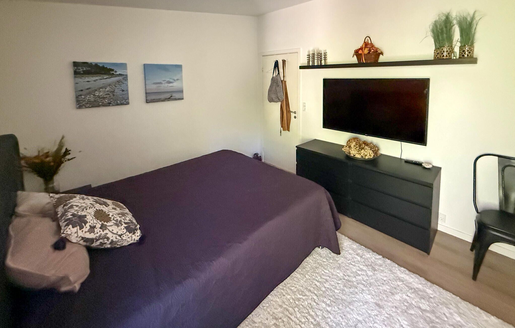 A bedroom with a bed, a TV, a dresser, and a chair.