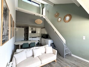 Ein kompakter Wohnbereich mit Küchenzeile, einer Couch, einem Essbereich und einer Treppe.