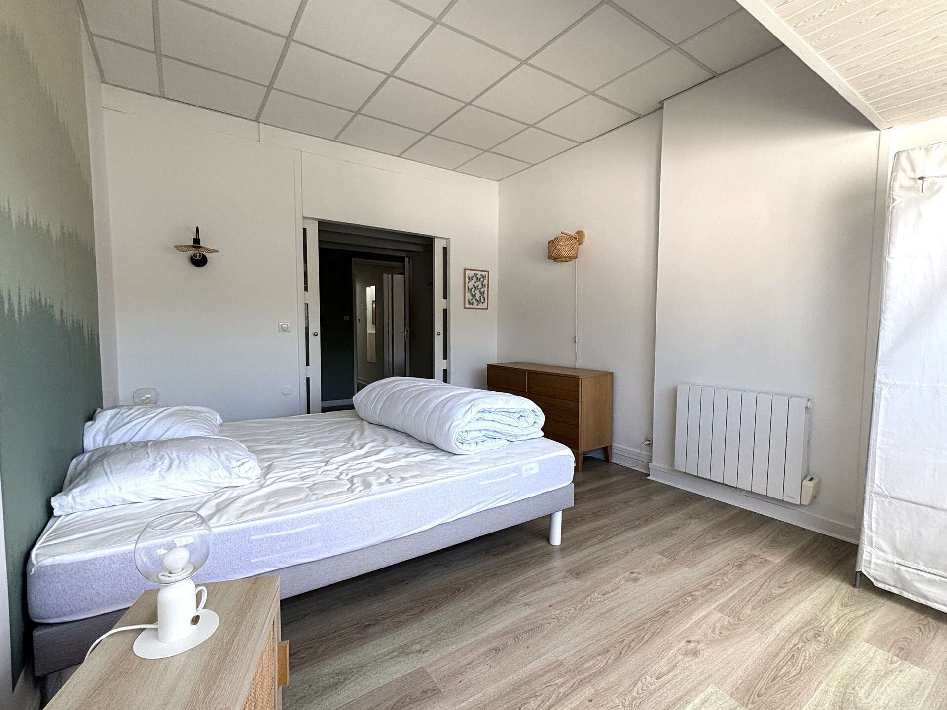 A bedroom with a bed, bedside table, and a radiator.