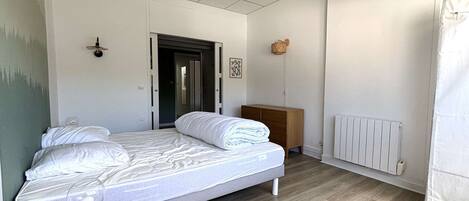 A bedroom with a bed, bedside table, and a radiator.