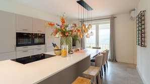 Una cocina moderna con una isla central, taburetes de bar y un jarrón decorativo con flores.