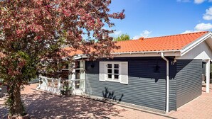 A small, single-story building with a dark exterior, a red-tiled roof, and a white-framed window. - 4 bedroom awesome home in Slagelse (Slagelse)