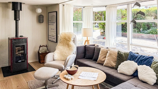 A cozy living room with a fireplace, a sofa, a chair, and a table with candles. - 4 bedroom awesome home in Slagelse (Slagelse)