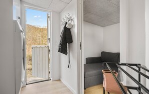 A narrow hallway with a door leading outside, a grey sofa, and a black jacket hanging on the wall. - Lovely home in Slagelse with house sea view (Slagelse)