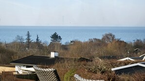 Paesaggio costiero con una casa, una sedia e vista sul mare.