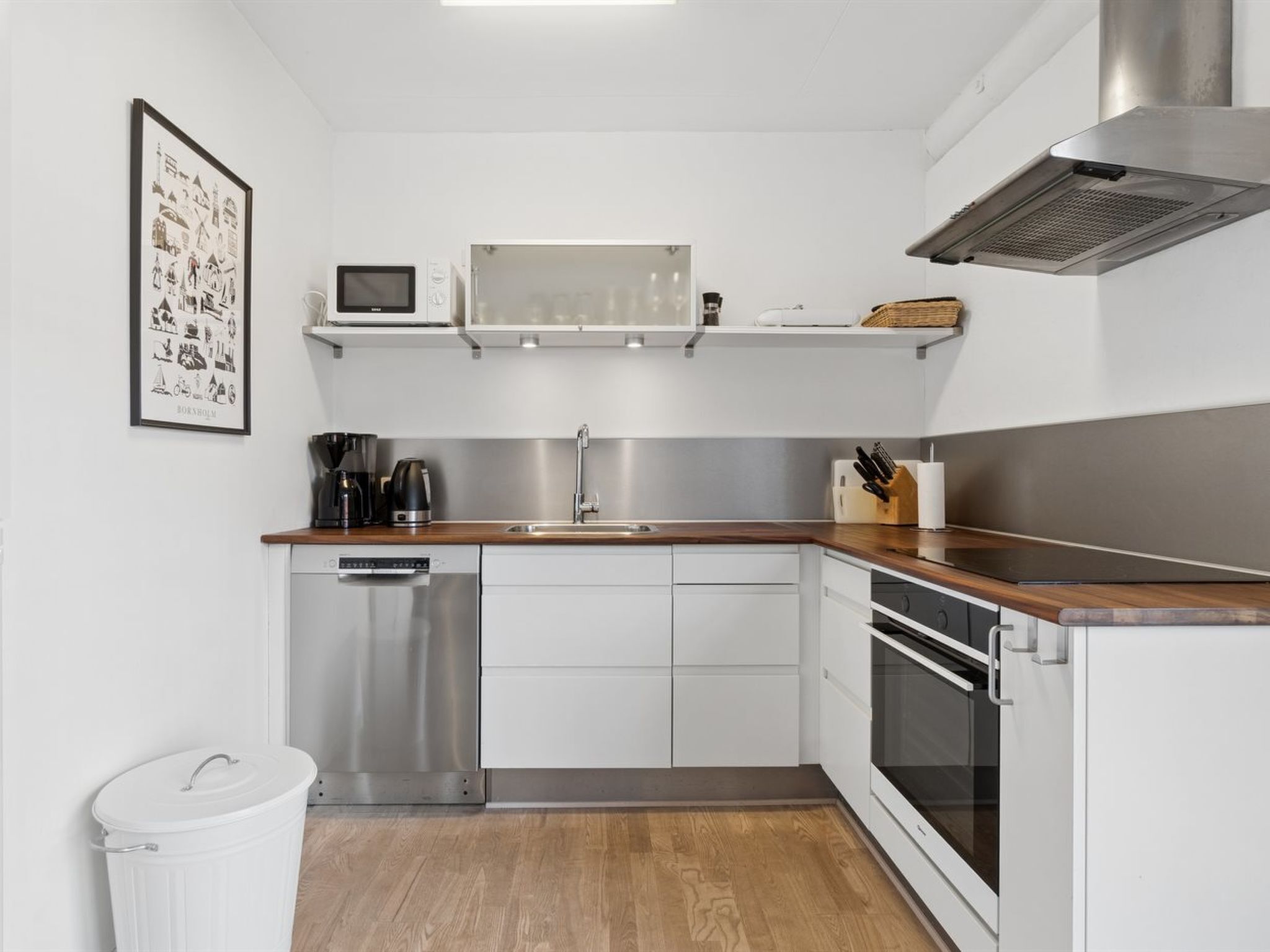 A modern kitchen with stainless steel appliances, a dishwasher, and a wooden countertop.