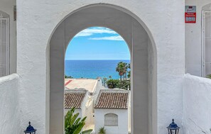 Ein Bogen führt zu einem Blick auf das Meer und ein Gebäude mit einem Ziegeldach.