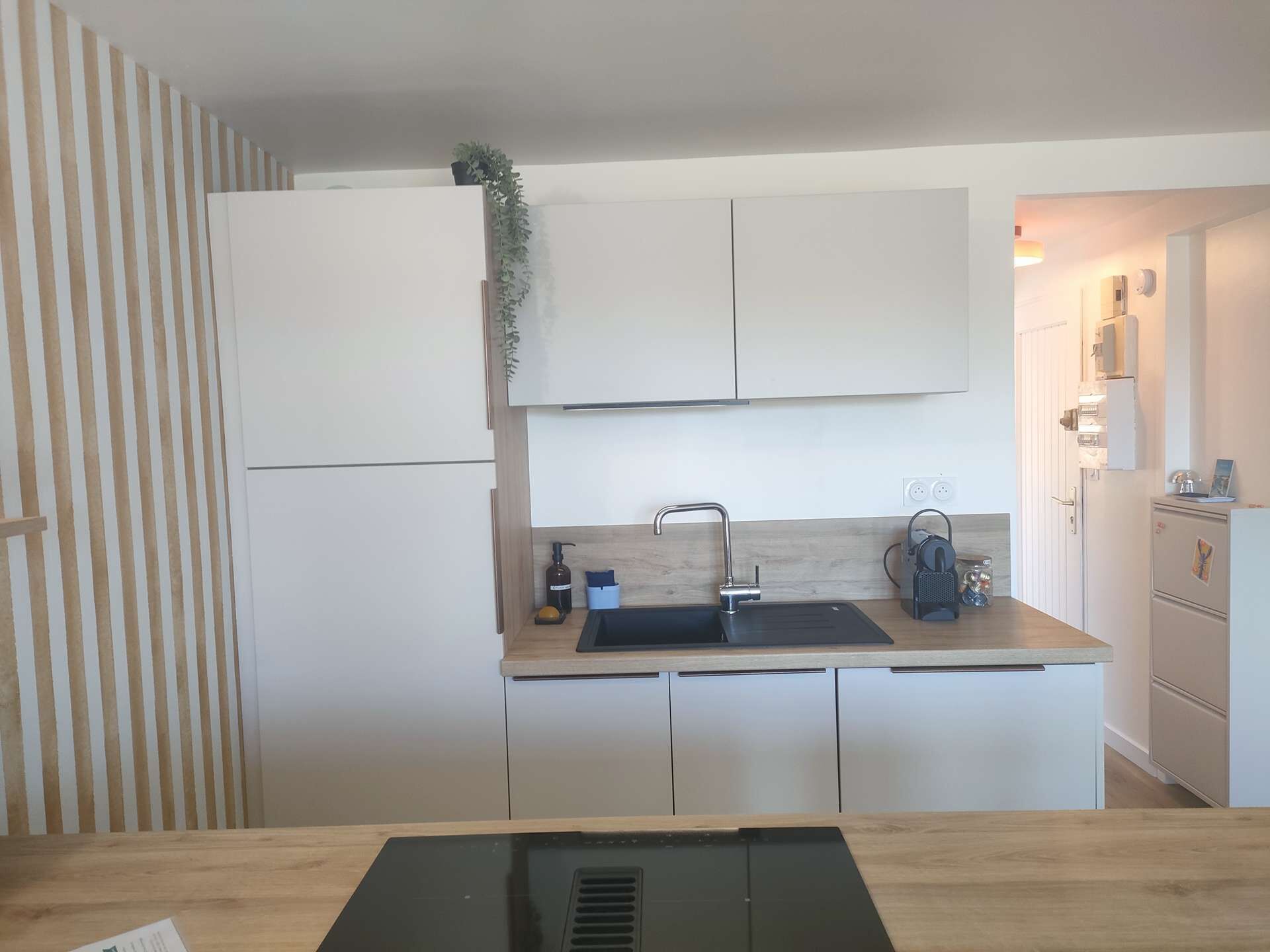 A kitchen with white cabinets, a black sink, and a wooden countertop.