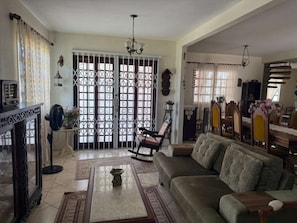 A living room with a sofa, a coffee table, a rocking chair, a television, and a decorative fan. - Casa Floripa - Praia Daniela, 5-7 pessoas, 300m da Praia - 4 Estacoes (Florianópolis)