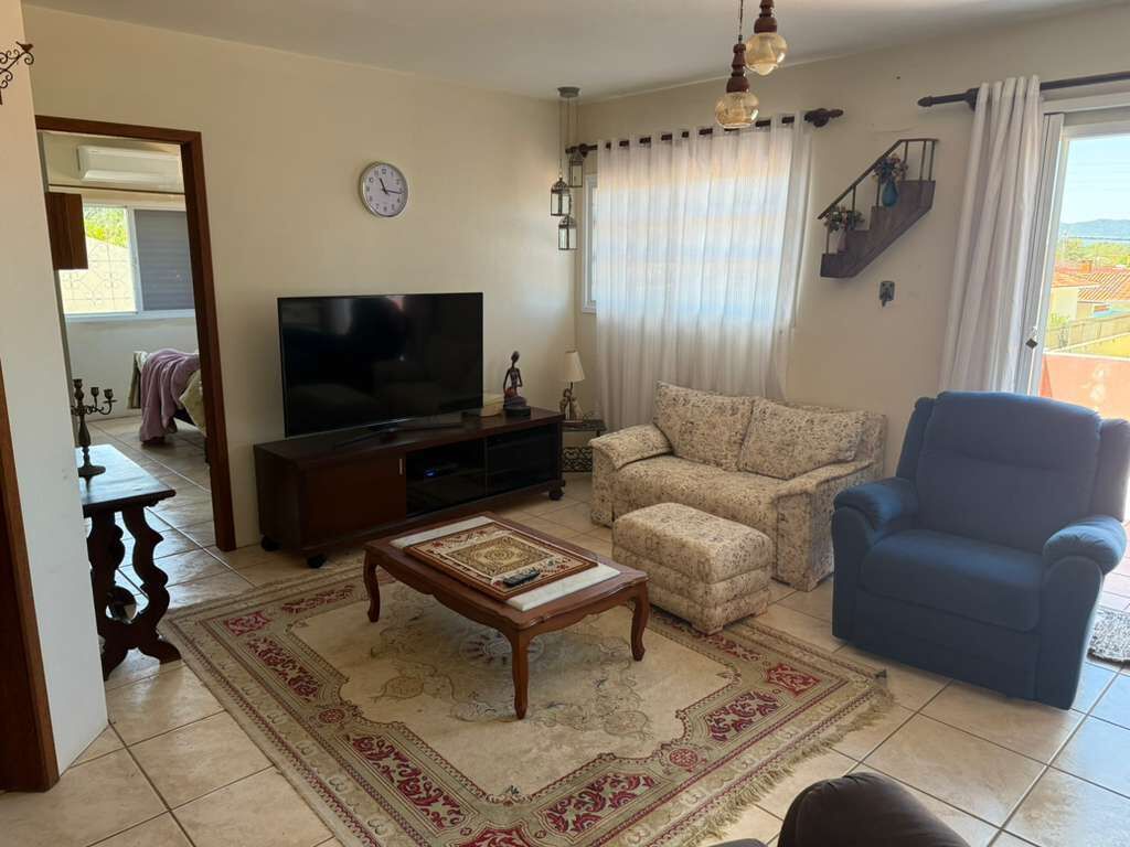 A living room with a TV, sofa, armchair, and a staircase.