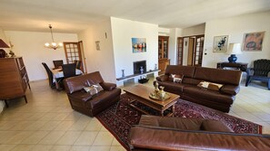 Ein Wohnzimmer mit einer Sofagarnitur, einem Couchtisch, einem Kamin und einem Essbereich mit Stühlen und einem Tisch.