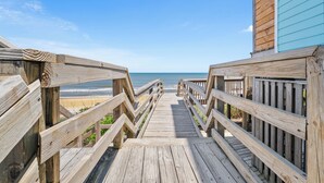 A wooden boardwalk leading to a beach with a clear view of the ocean.