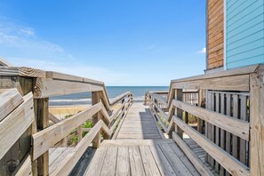 Ein Holzsteg führt zu einem Strand mit freiem Blick auf das Meer.