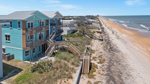 A beachfront property with a multi-story building, wooden walkways, and a sandy beach.
