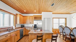 A kitchen with wooden cabinets, a central island, bar stools, and a refrigerator.