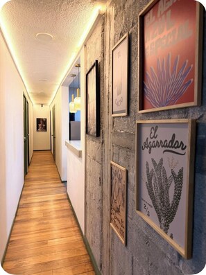 A hallway with wooden flooring, framed artwork on the walls, and a ceiling with recessed lighting. - Casa Agaveria -Boutique Stay in Condesa ( 4 bedrooms + Balconies) (Ciudad de México)