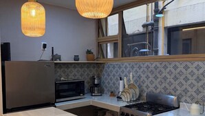 Ett modernt kök med en stor köksö, rostfria vitvaror och ett mönstrat stänkskydd.