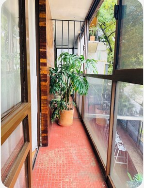 A narrow corridor with a tiled floor, a potted plant, and a view of the outside. - Casa Agaveria -Boutique Stay in Condesa ( 4 bedrooms + Balconies) (Ciudad de México)
