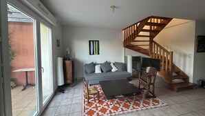 A living room with a grey sofa, wooden staircase, and a patterned rug.