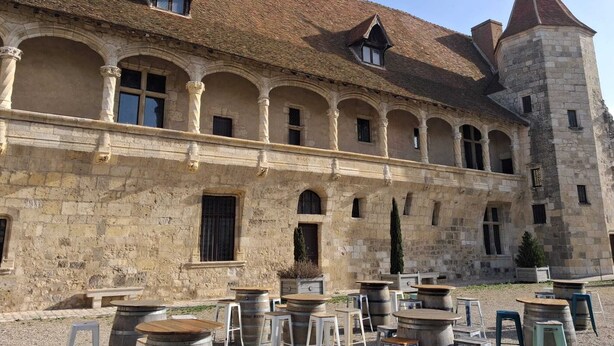 A historic building with a courtyard, stone walls, and a tower.