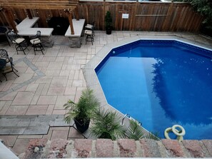 A backyard with a swimming pool, patio furniture, and a wooden fence.