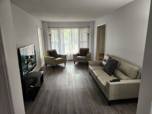 A living room with a flat-screen TV, two armchairs, a sofa, and a coffee table.