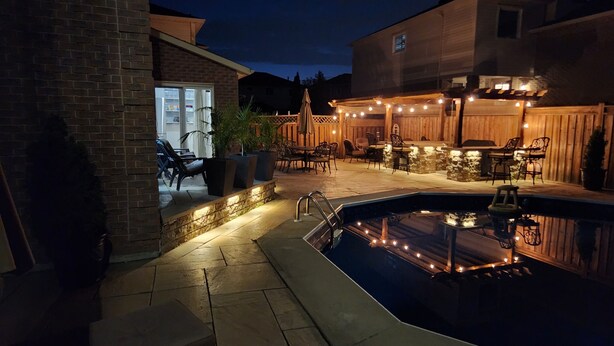 Ein Poolbereich mit Terrasse, Sitzgelegenheiten im Freien und einem Backsteinhaus.