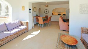 Ein Wohnzimmer mit einer Couch, Stühlen, einem Esstisch und einer Küche im Hintergrund.