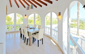 A dining area with a table, chairs, and large windows with a view of greenery. - Beautiful home in Calpe (Calpe)