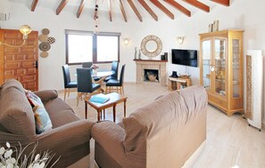 A living room with a sofa, a dining table with chairs, a fireplace, a television, and a cabinet. - Beautiful home in Calpe (Calpe)