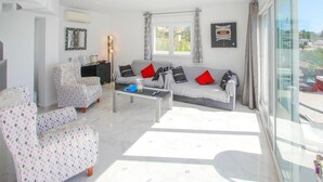 A modern living room with a sofa, armchairs, a coffee table, and a large window with curtains. - Stunning home in Benissa (Benissa)