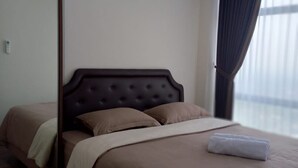 A hotel room with a large bed, a dark headboard, and a window with curtains. - Grand Sungkono Lagoon Caspian Apartment 1BR (Surabaya)