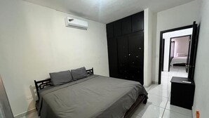 Un dormitori amb llit, un armari i una porta que dona a una altra habitació.