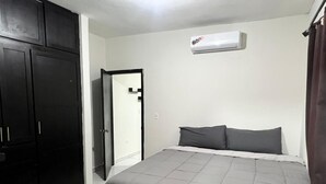 Un dormitori amb llit, armari, una porta i aire condicionat.