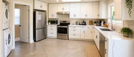 A modern kitchen with white cabinets, stainless steel appliances, and a built-in oven.
