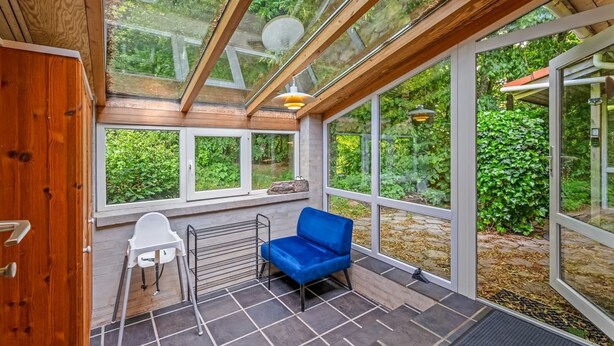 Una habitación con tragaluz, una silla azul, una mesa blanca y un radiador.