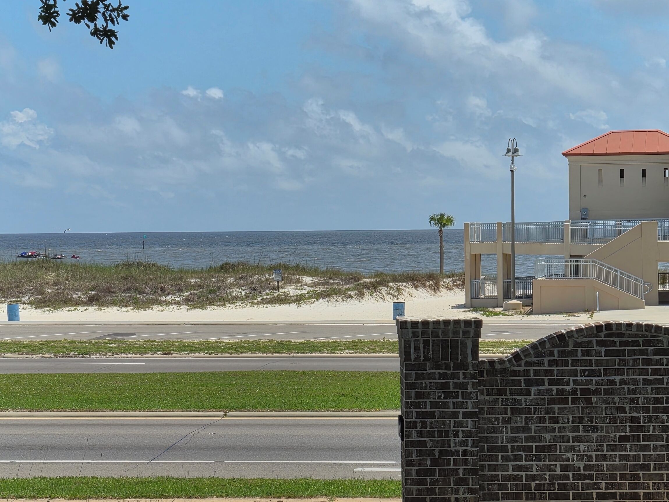 Une vue sur la plage avec un bâtiment, une route et un ciel dégagé.