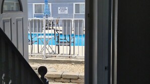 Area piscina con cartello di avviso per i bagnini, tavolo da biliardo e zona relax coperta.