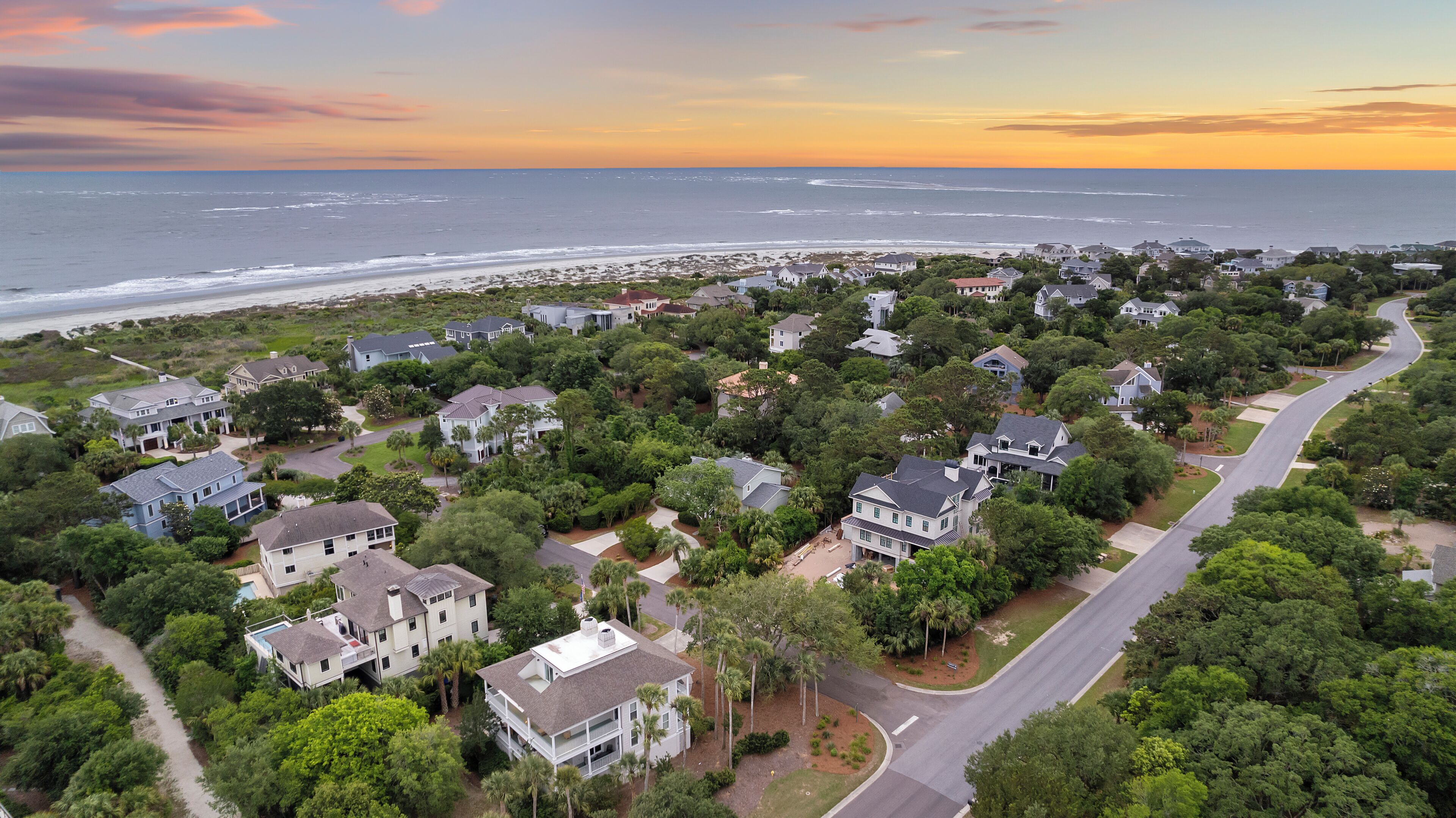 Vue aérienne d’une zone résidentielle côtière, avec des maisons, des routes et une plage.