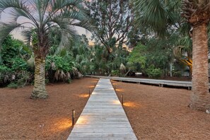 A wooden pathway leading through a garden with various trees and plants. - Steps to the Beach on Seabrook! Family Favorite w/ Club Access (Seabrook Island)