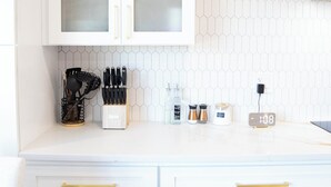 Una cocina con armarios blancos, salpicadero de azulejos hexagonales y un reloj que marca las 10:08.