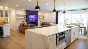 Una cocina moderna con una isla central, electrodomésticos integrados e iluminación colgante.