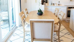 Una cocina moderna con armarios blancos, una mesa de comedor de madera y sillas.