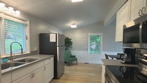 A modern kitchen with stainless steel appliances, a wooden floor, and a view of the living area. - Gorgeous, fully renovated 3-bedroom house with AC in tranquil La Vale (La Vale)