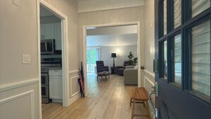A hallway with a wooden floor, a dining area with a table and chairs, a kitchen with appliances, and a door with a window. - Gorgeous, fully renovated 3-bedroom house with AC in tranquil La Vale (La Vale)