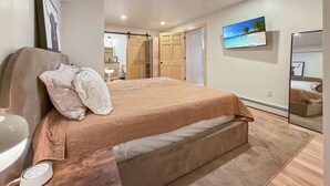 Un dormitorio con cama, mesita de noche, televisor, espejo y armario.
